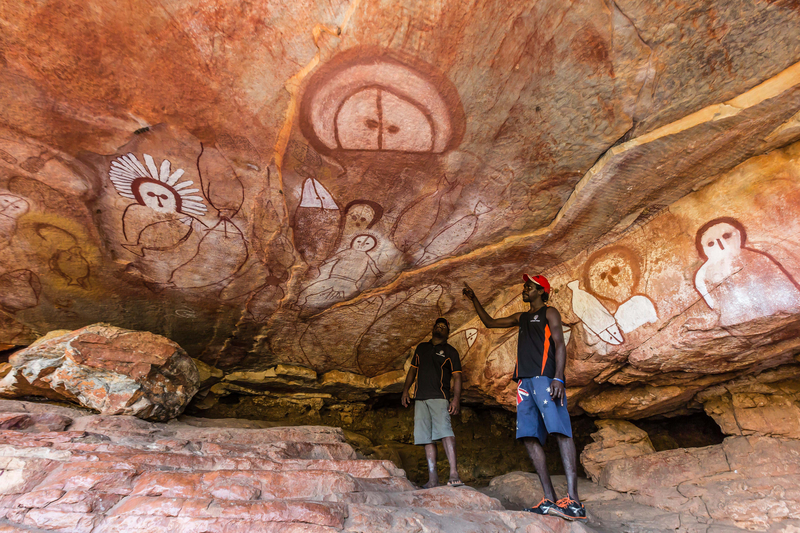 Aboriginal guides presenting Wandjina cave artwork in sandstone caves at Raft Point, Kimberley, Western Australia, Australia