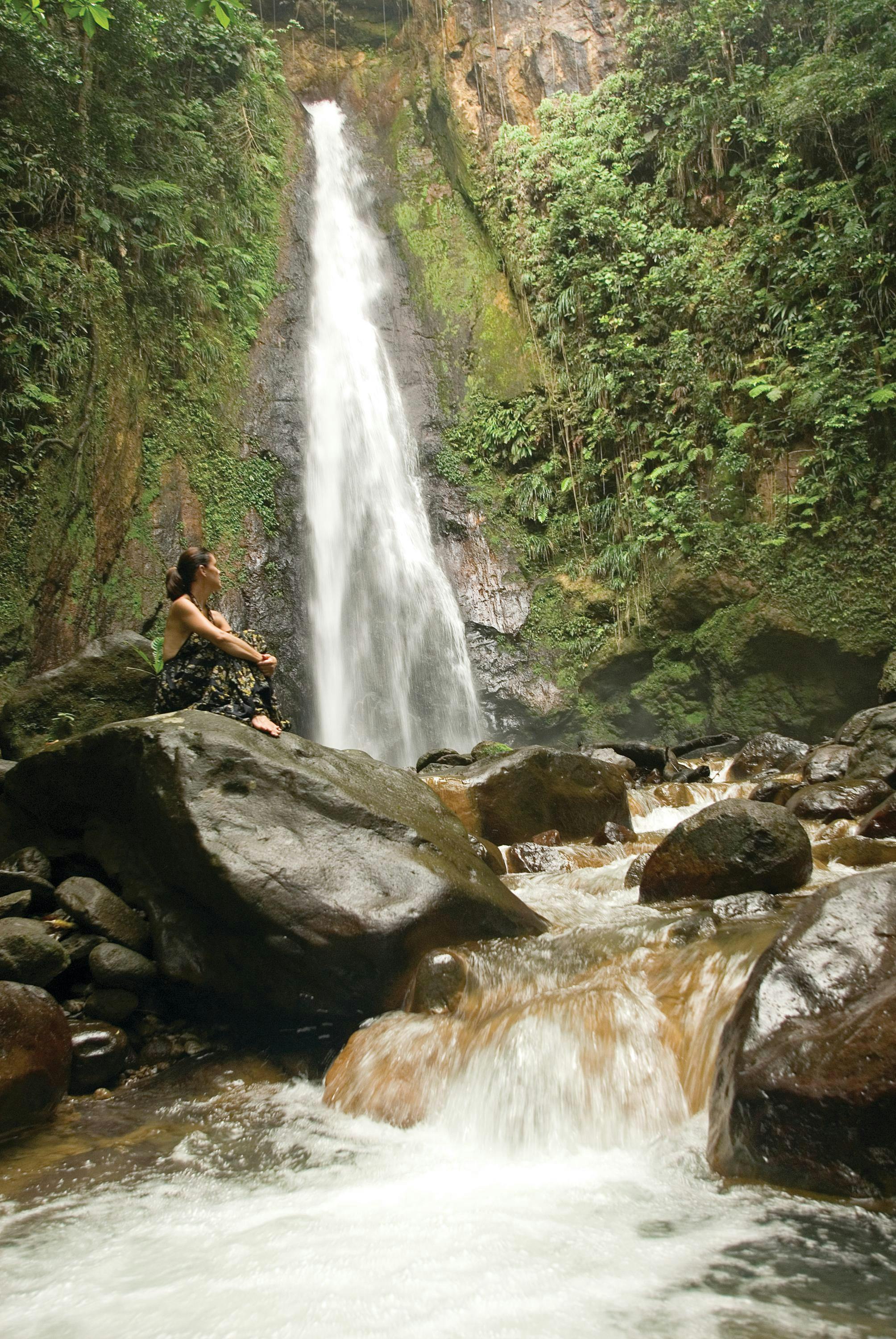 Traveler, Maria Lindblad,  sits and enjoys a waterfall in Dominica, Caribbean