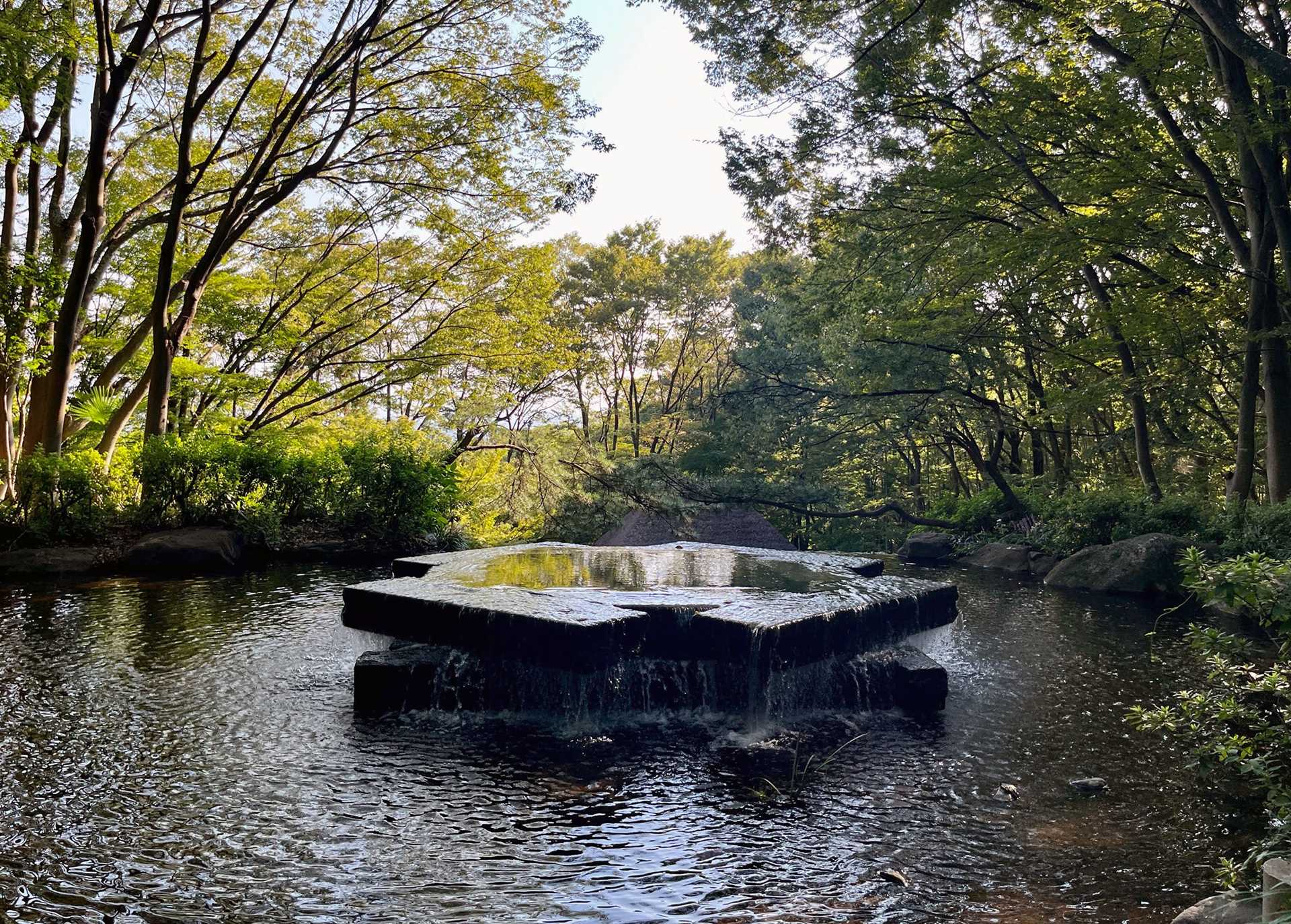 a flat black fountain in a japanese garden