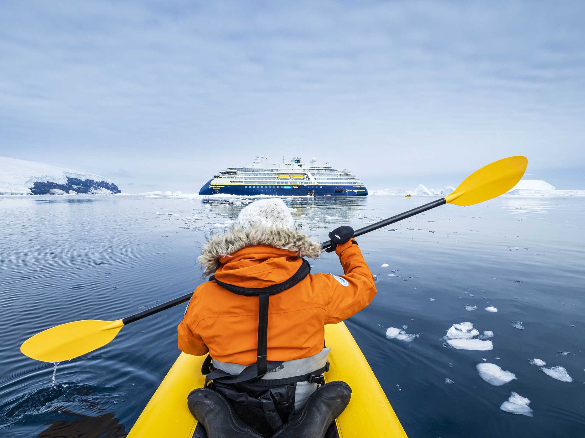 Guest kayaking off Peter 1 Island with the National Geographic Resolution in the distance.