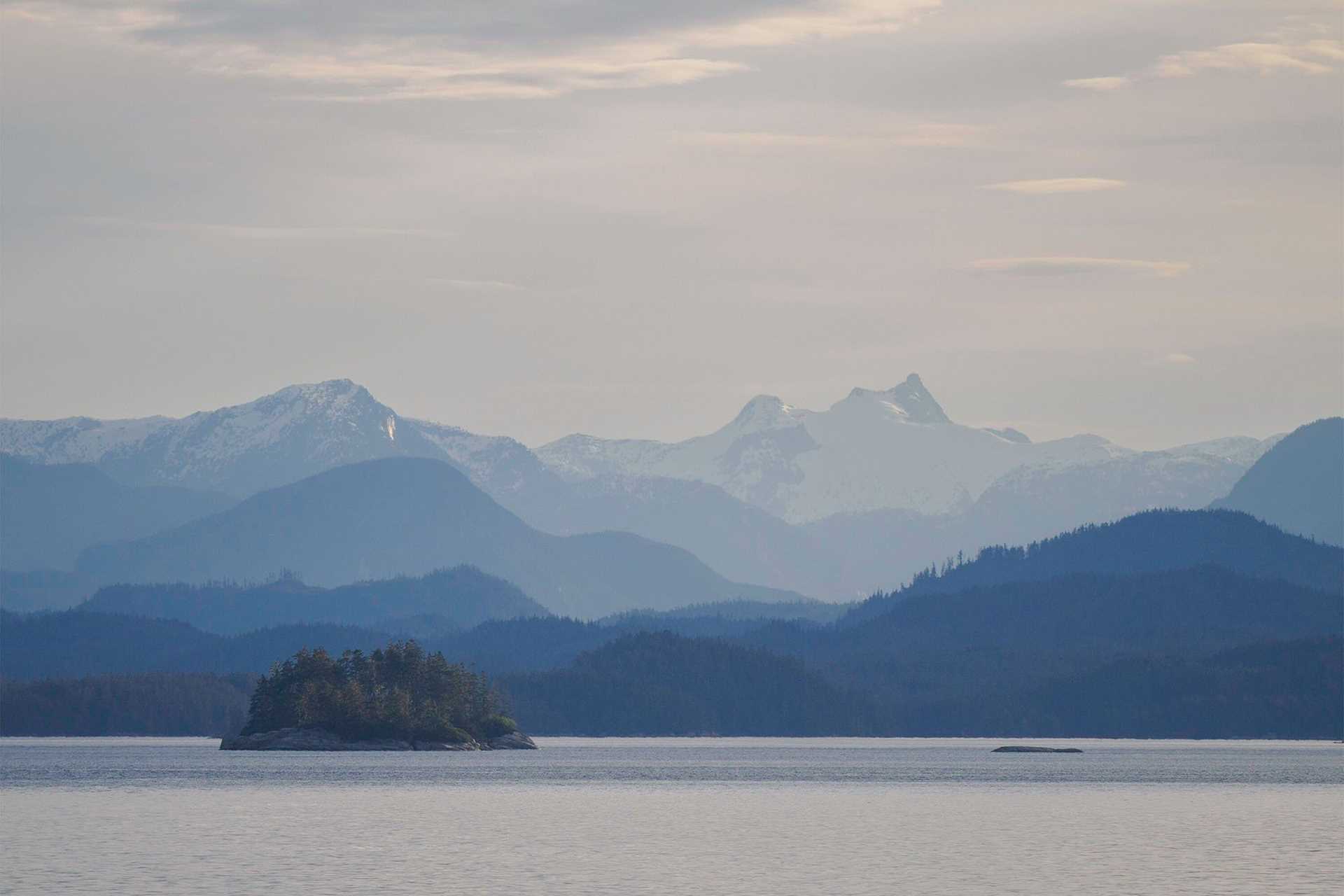 mountains shrouded in mist, with an island in the foreground