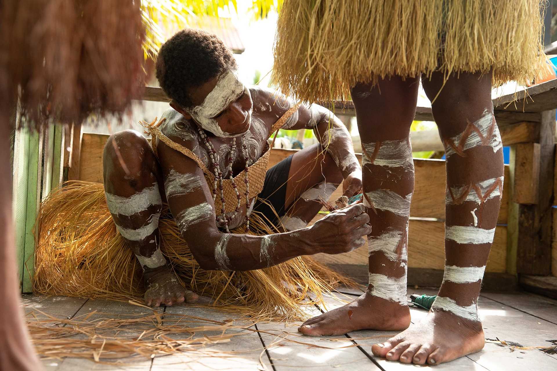 young Asmat dancer painting another dancer's legs