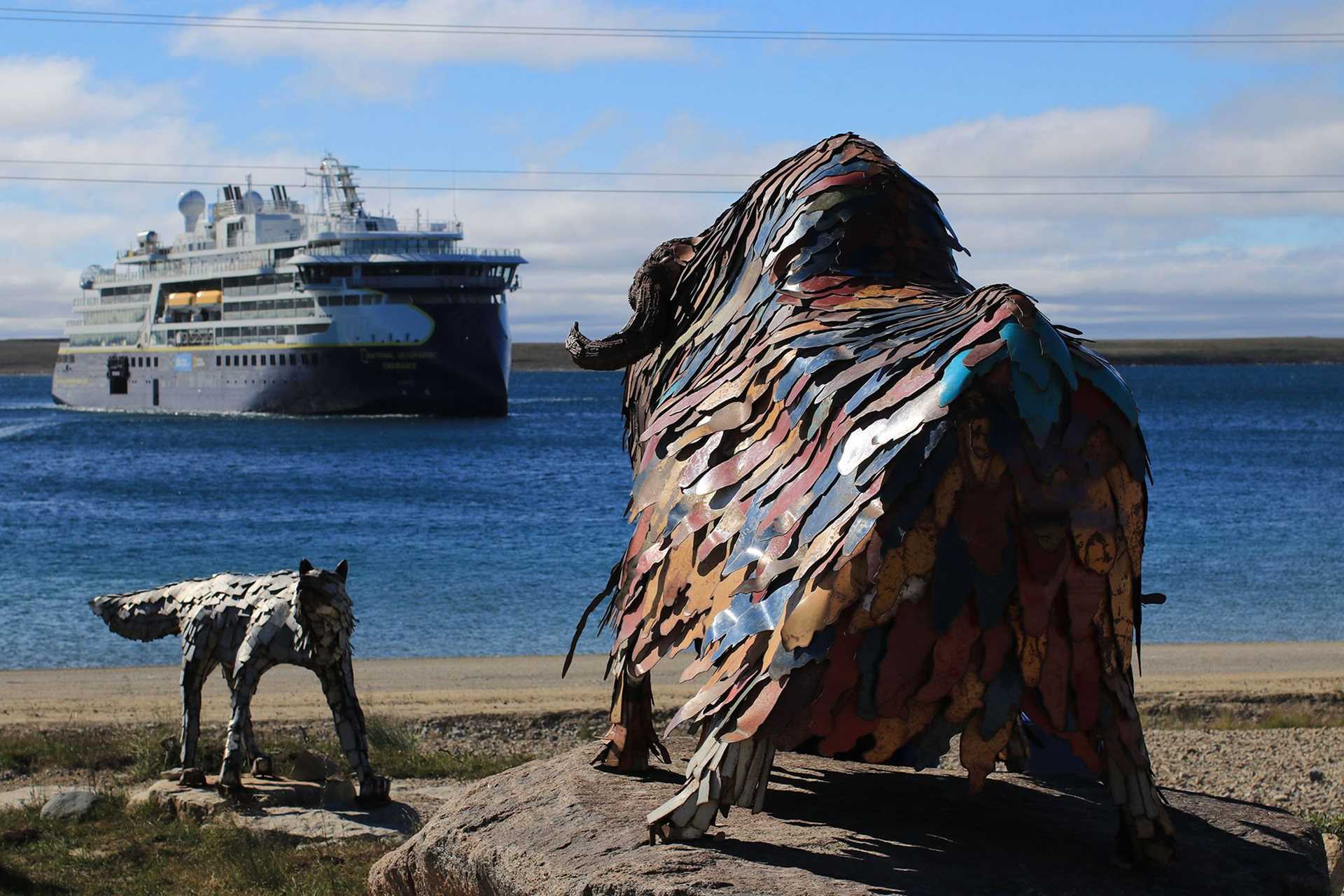 metal sculpture of bison and wolf with ship in background