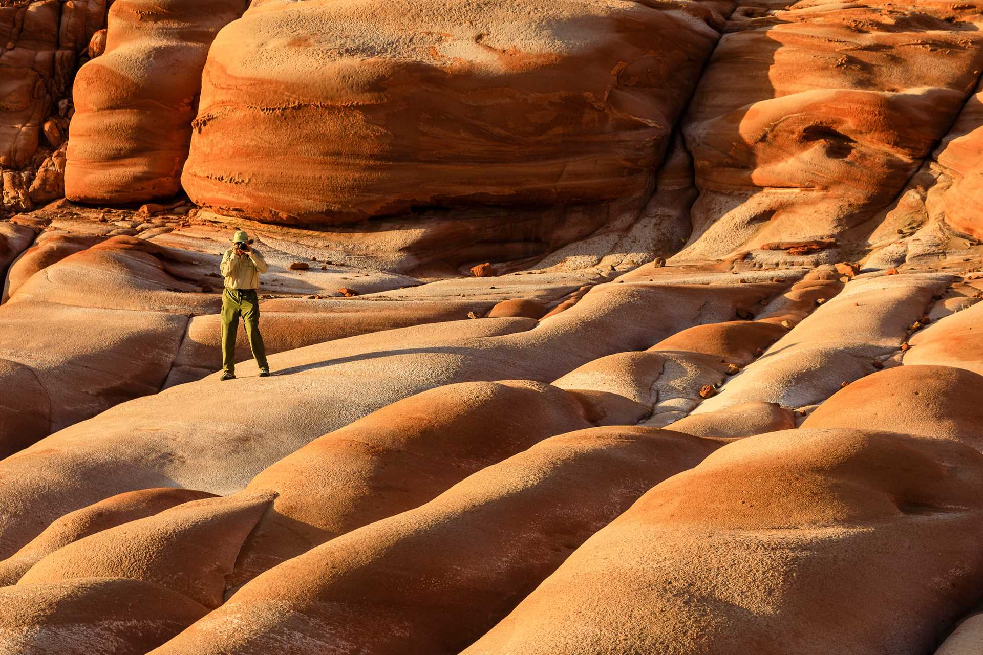 A guest hikes and photographs the red sandstone at Punta Gato, Baja California Sur, Mexico.