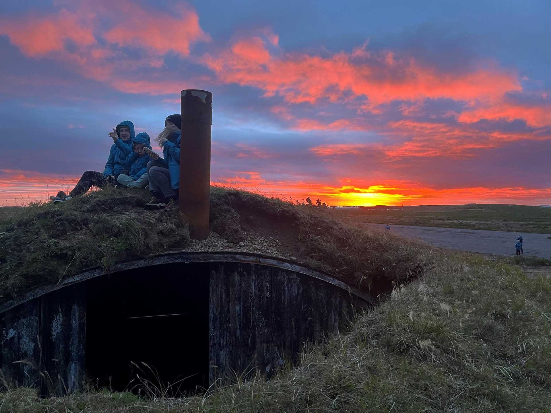 three people sit on a bunker watching volcanic activity in Iceland