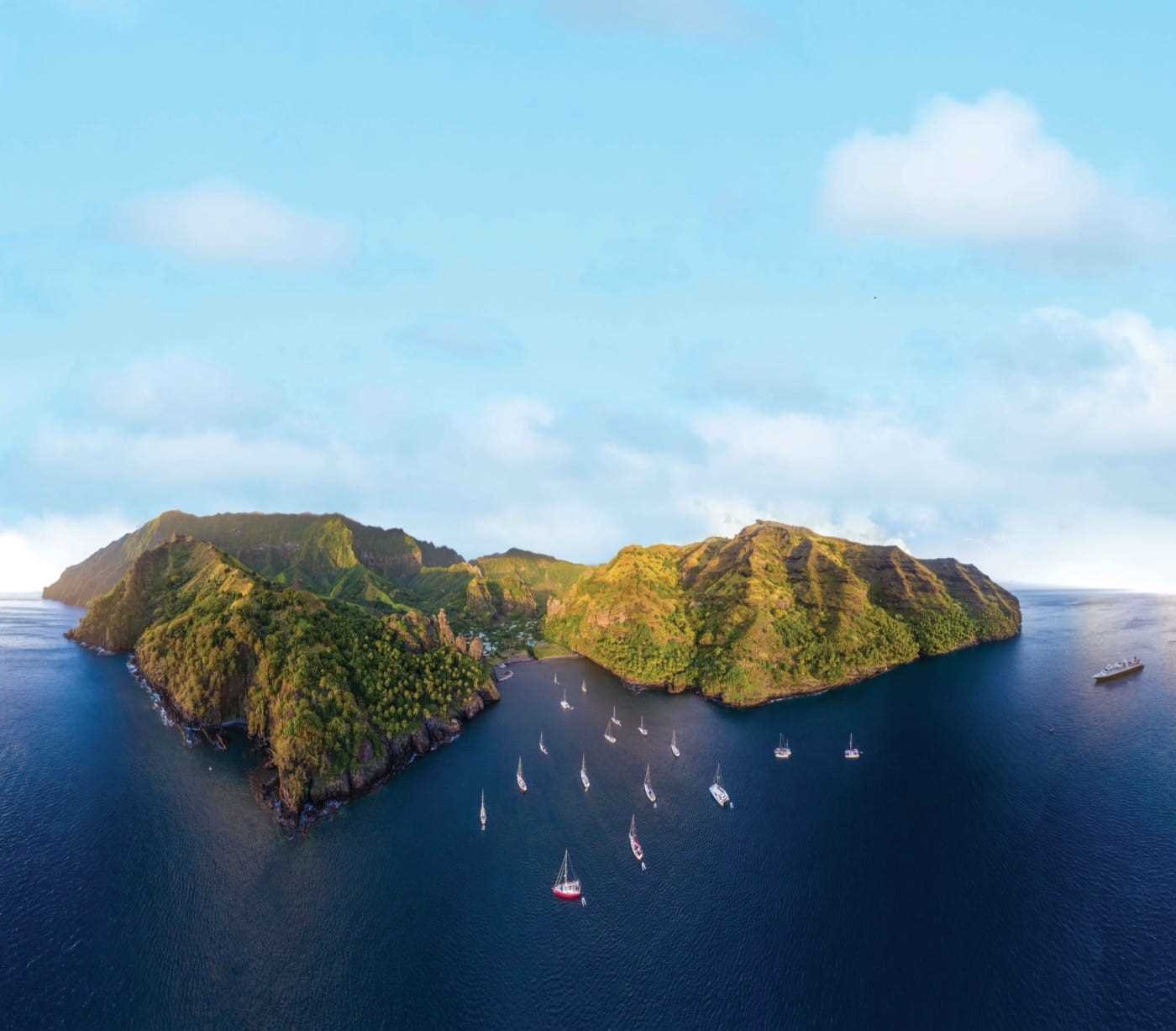 A bird's-eye view from the ocean, looking into an island's bay where ships gather