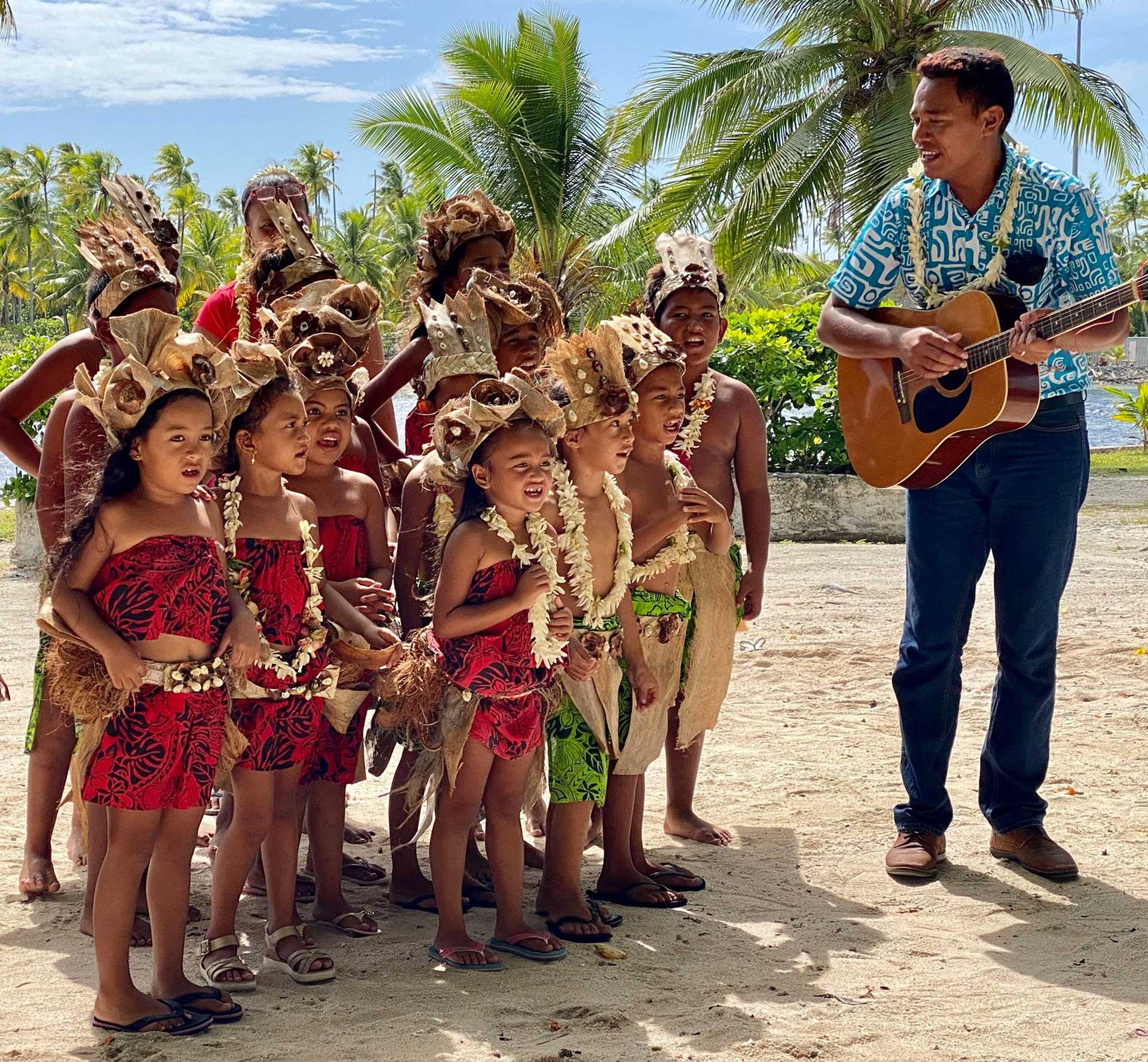 a man playing a guitar while children sing
