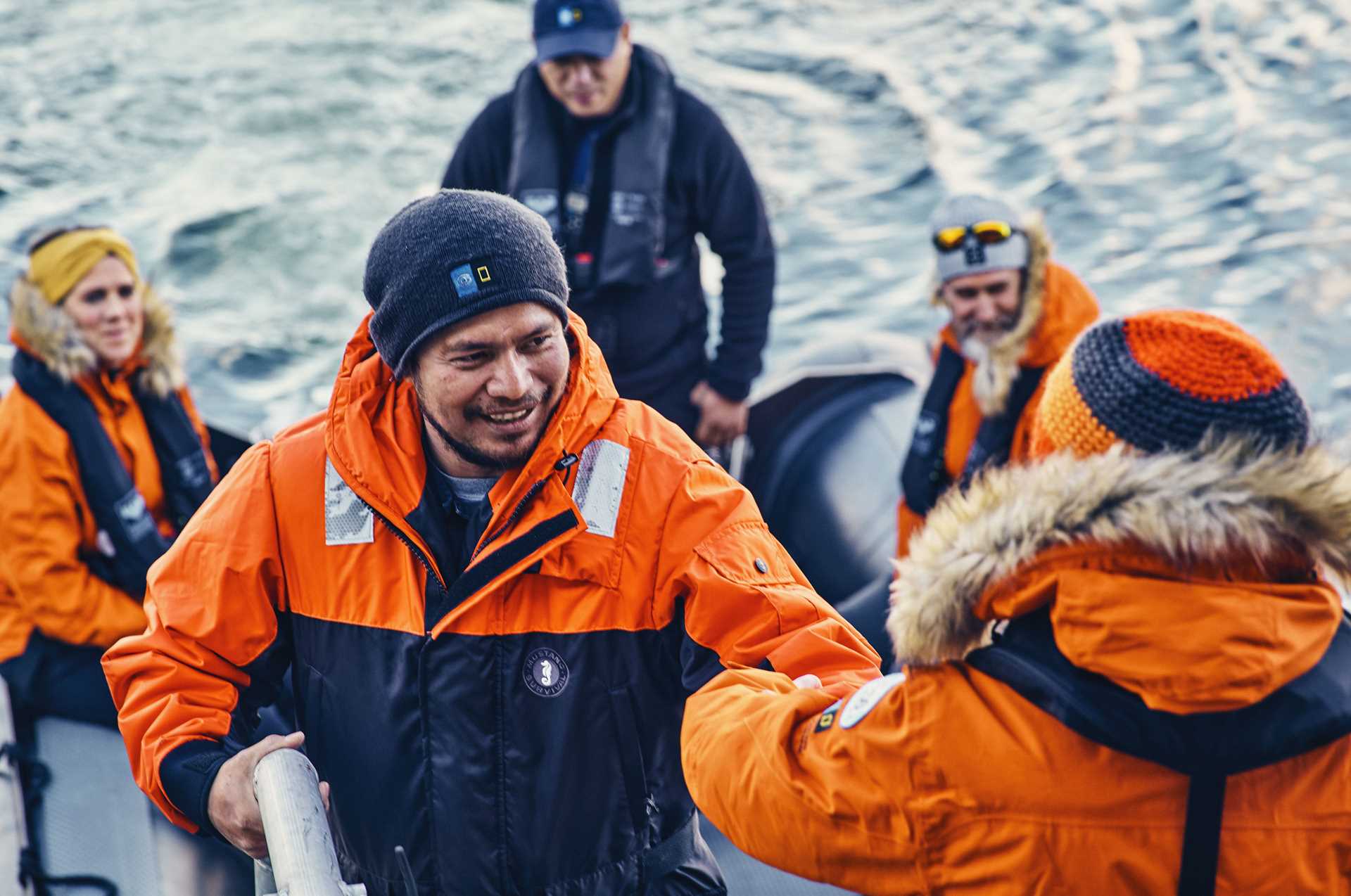 A crew member helps a guest board a Zodiac.