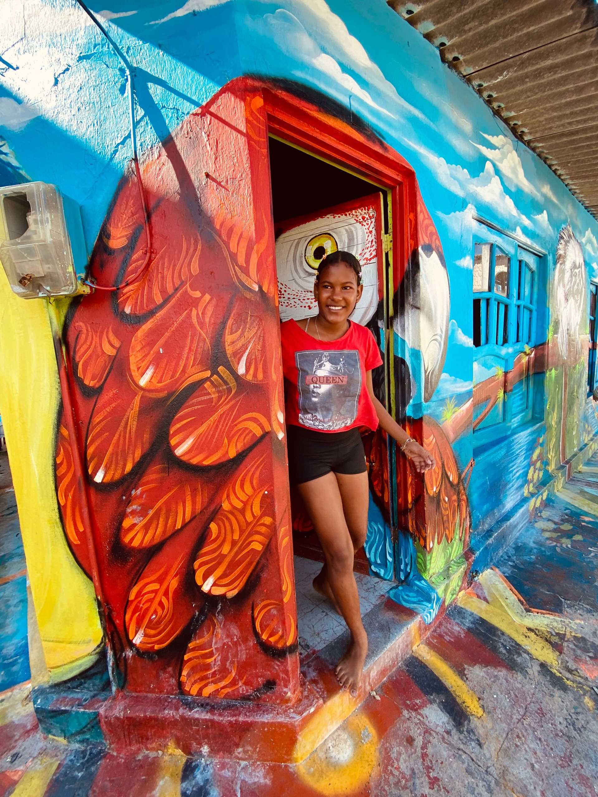 woman standing in front of a mural of a parrot
