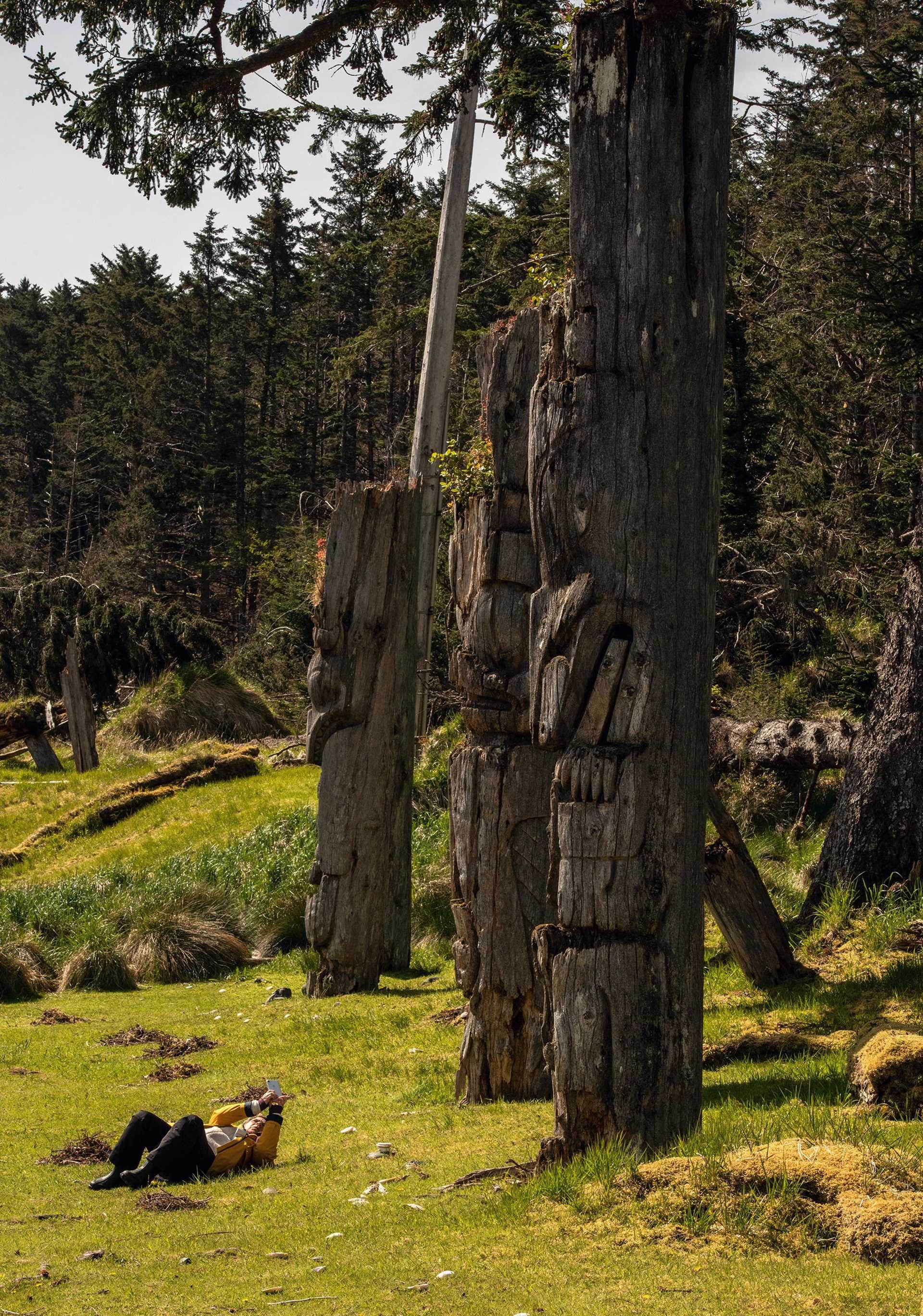 a photographer sits in front of totem poles