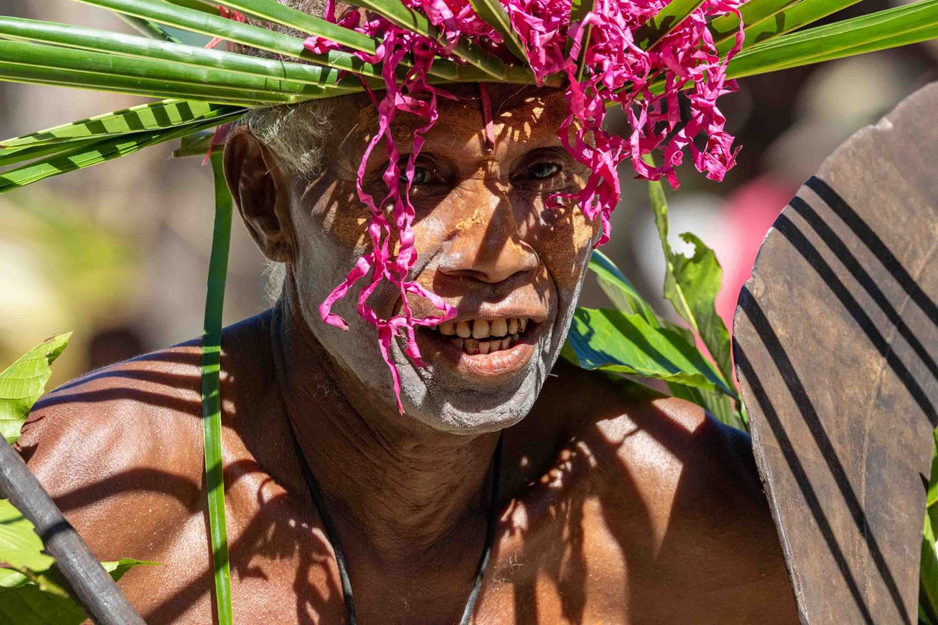 close up of man with painted face and hat made of leaves
