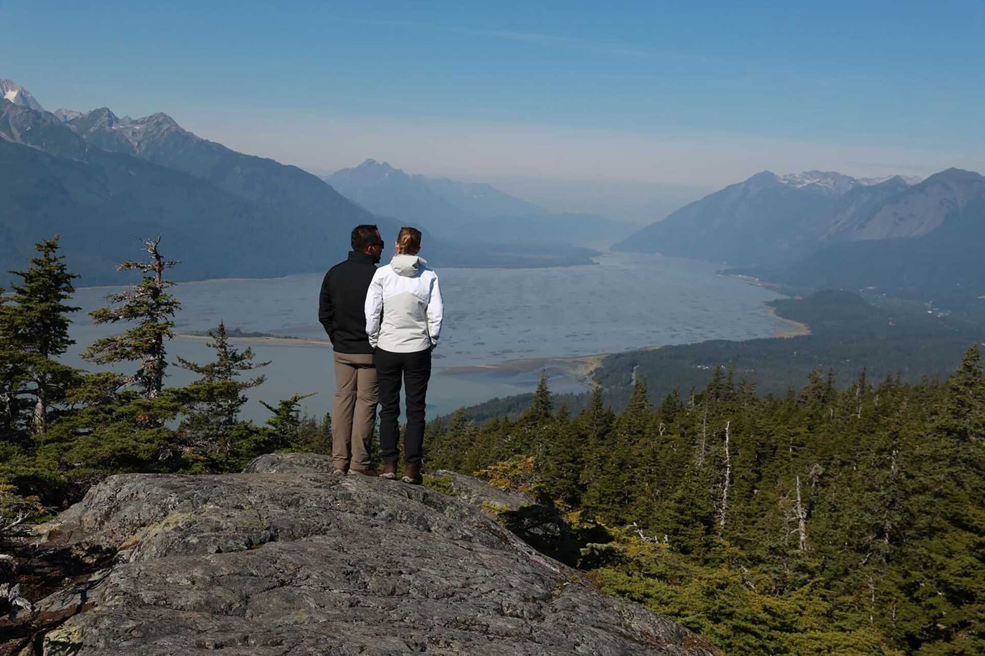 a couple stands on a cliff in alaska